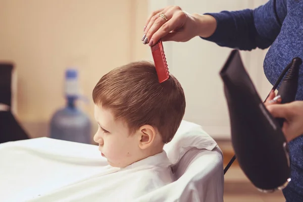 Руки парикмахера делают прическу маленькому мальчику, закрываются — стоковое фото