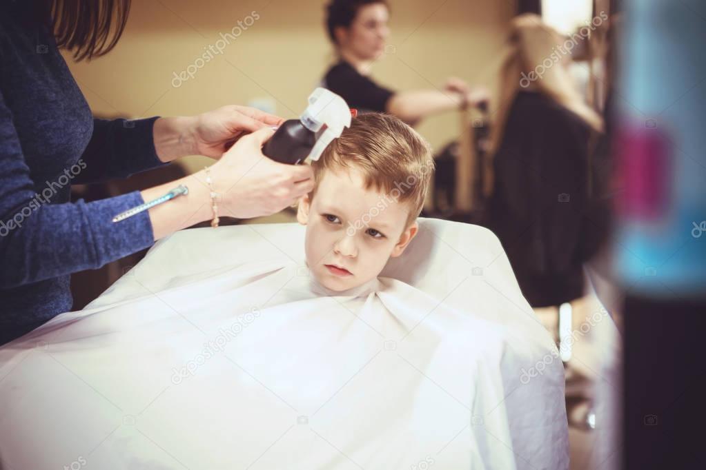 Little boy at the hairdresser. Child is scared of haircuts. Hair