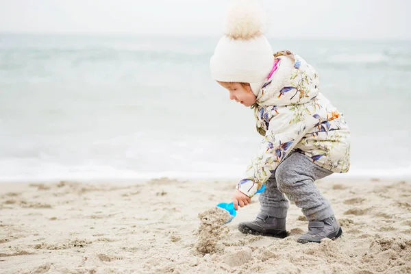 Cute little girl playing on the sandy beach. Happy child wearing — Stock Photo, Image