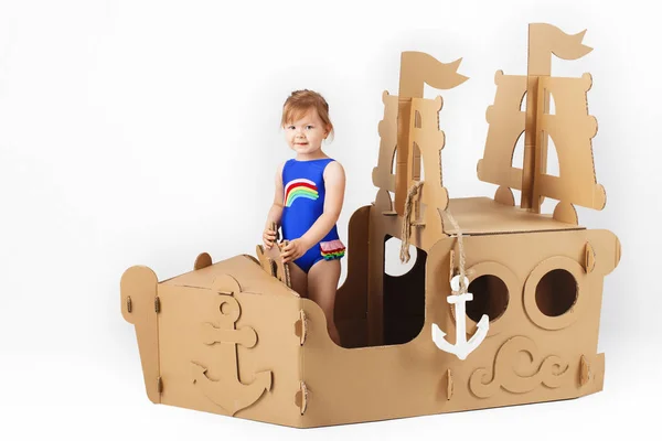 Cute Little girl wearing bright swimsuit playing with cardboard