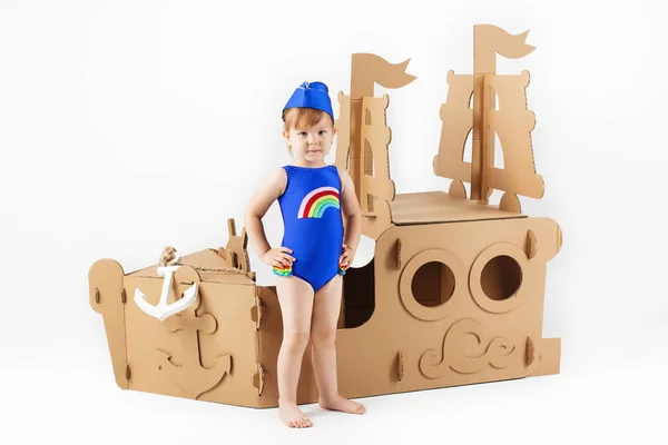 Cute Little girl wearing bright swimsuit playing with cardboard — Stock Photo, Image