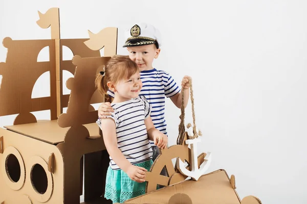 Crianças brincando com o navio de papelão no fundo branco. Hap — Fotografia de Stock