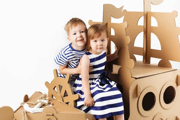 Kleine Kinder spielen mit einem Pappschiff auf weißem Hintergrund. hap — Stockfoto