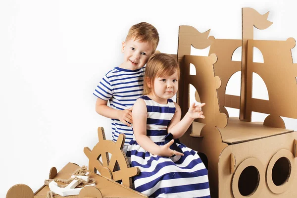 Little kids playing with cardboard ship on white background. Hap — Stock Photo, Image