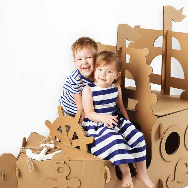 Little kids playing with cardboard ship on white background. Hap — Stock Photo, Image