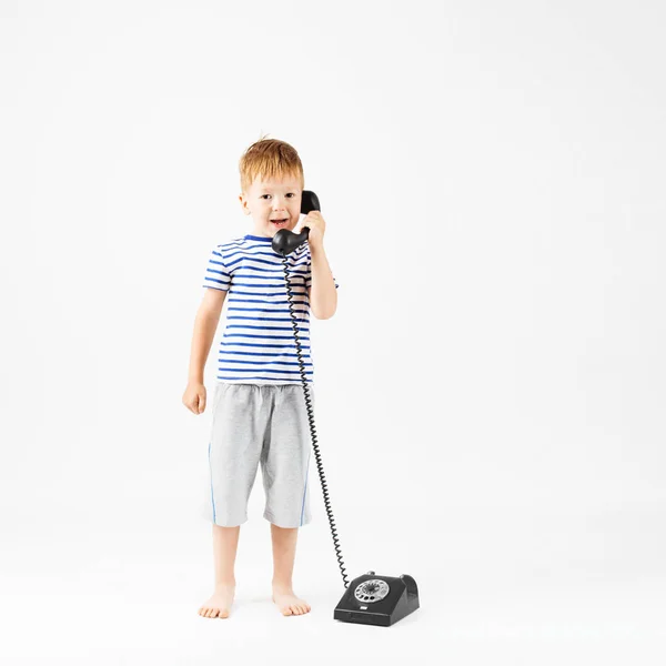 Petit garçon avec téléphone rétro contre un blanc — Photo