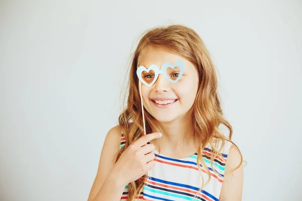 Encantadora niña con divertido partido de papel corazón forma gafas o — Foto de Stock