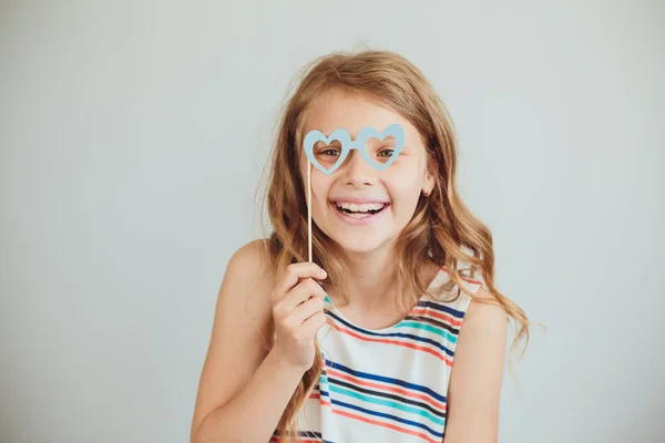 Schöne kleine Mädchen mit lustigen Party-Papier herzförmige Gläser oder — Stockfoto