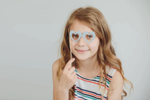 Милая маленькая девочка с смешной стороны бумажные очки формы сердца или — стоковое фото