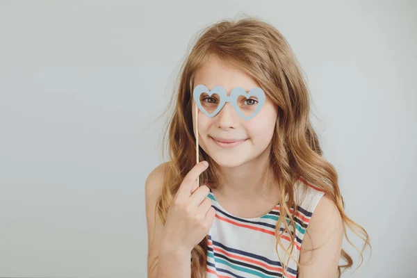 Encantadora niña con divertido partido de papel corazón forma gafas o — Foto de Stock