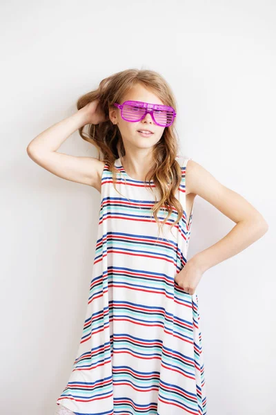 Härlig liten flicka i en randig klänning med rolig part plast s — Stockfoto