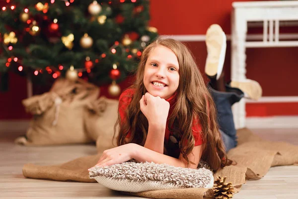 Симпатичная улыбающаяся девочка-подросток с длинными волосами в интерьере с Кристмой — стоковое фото