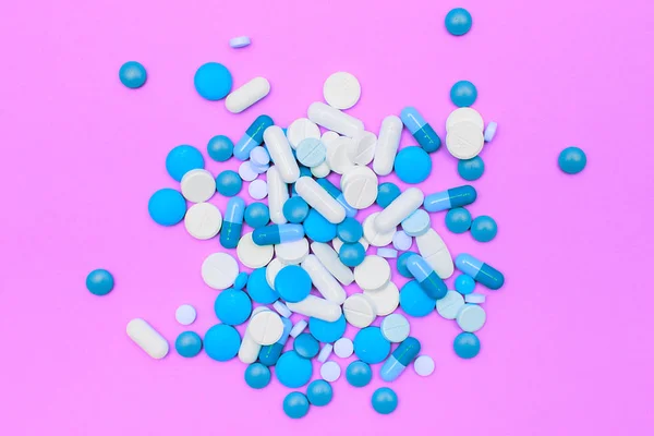 Капсулы с лекарствами и таблетки на розовом фоне . — стоковое фото