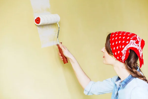 Hermosa chica en rojo Diadema pintura de la pared con rollo de pintura — Foto de Stock