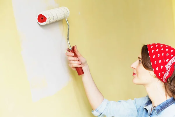 Hermosa chica en rojo Diadema pintura de la pared con rollo de pintura — Foto de Stock