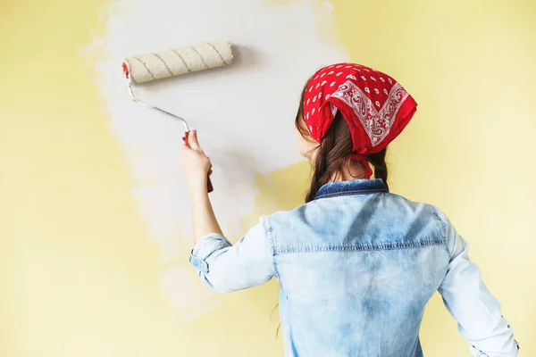 Bella ragazza in fascia rossa dipingere il muro con rullo di vernice — Foto Stock