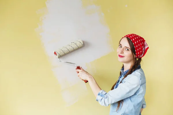 Bella ragazza in fascia rossa dipingere il muro con rullo di vernice — Foto Stock