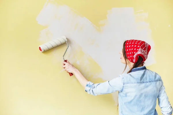 Bella ragazza in fascia rossa dipingere il muro con rullo di vernice — Foto Stock