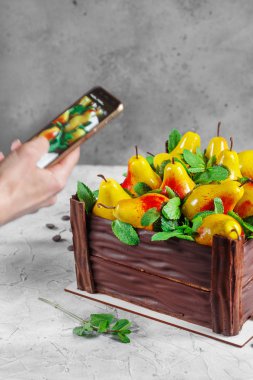 Kız akıllı telefonuyla armut kekinin fotoğrafını çekiyor. Doğum günü pastası...