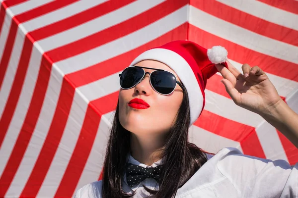 Retrato de uma menina bonita em chapéu de Papai Noel e óculos de sol — Fotografia de Stock