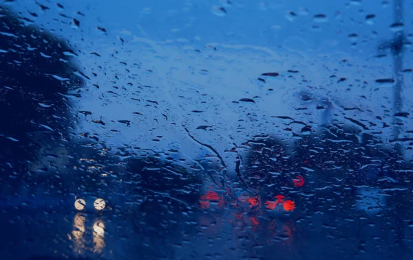 車のフロント ガラスに雨を通して見た都市道路を削除します。. — ストック写真