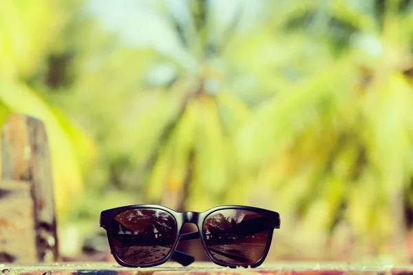 Gafas de sol de cerca tumbadas sobre una mesa de madera en trópicos con coco —  Fotos de Stock