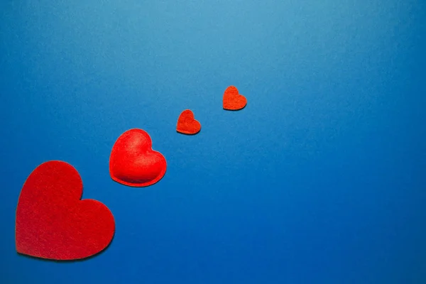 Decoratieve vilten harten op blauwe achtergrond. Abstracte achtergrond — Stockfoto