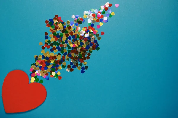 Decoratieve vilten hart met kleurrijke confetti op blauwe achtergrond. — Stockfoto