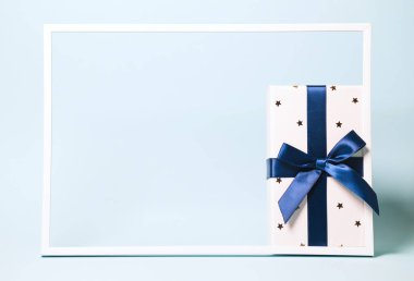 Renkli arka plan esprisine sarılı mavi kurdeleyle hediye kutusu