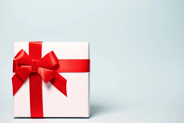 Caja de regalo envuelta con cinta roja sobre fondo colorido. Fez Imagen de archivo