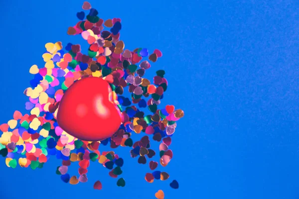 Decoratieve rode hart met kleurrijke confetti op blauwe achtergrond. — Stockfoto