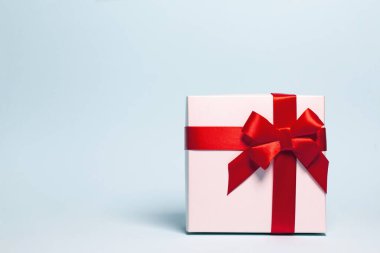 Pastel arka planda kırmızı kurdeleyle sarılı mevcut kutu. Şenlik ve tatil teması. Noel ya da doğum günü hediyesi. Satışlar ve alışveriş konsepti.