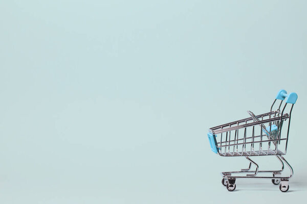 Маленькая декоративная тележка на пастельном фоне. Рождество или подарок на день рождения. Концепция продаж и покупок. Изображение с местом для копирования
