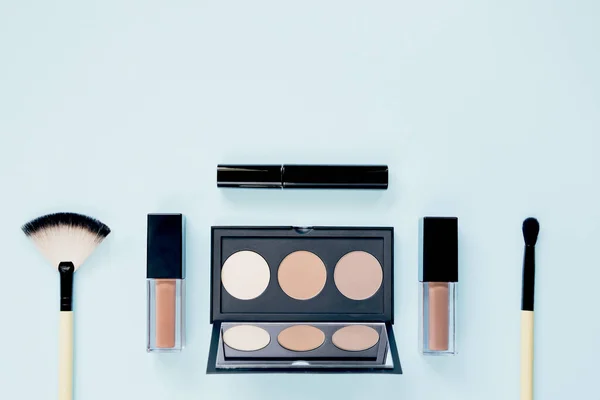 Renkli pastel arka planda makyaj fırçası ile dekoratif kozmetik seti. Asgari tarz kompozisyon. Üst görünüm