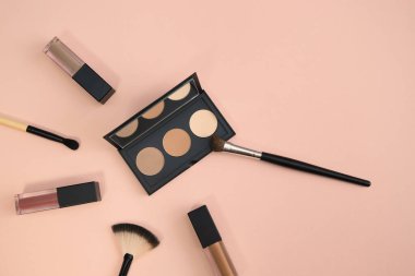 Renkli arka planda makyaj fırçaları olan dekoratif kozmetik seti. Asgari tarz kompozisyon. Üst görünüm