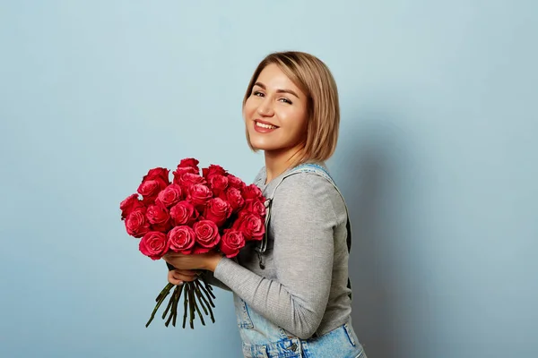 Beautiful girl in the overalls with red roses — Stock Photo, Image