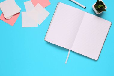 Ofis Masası not defteri, yapışkan notlar, kalem ve etli üstten görünüm mavi zemin üzerine