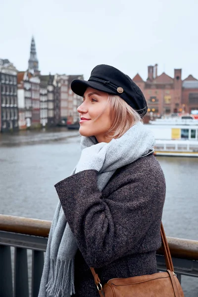 Jonge vrouw staat op de brug en kijkt naar het kanaal van Amsterdam, Nederland. — Stockfoto