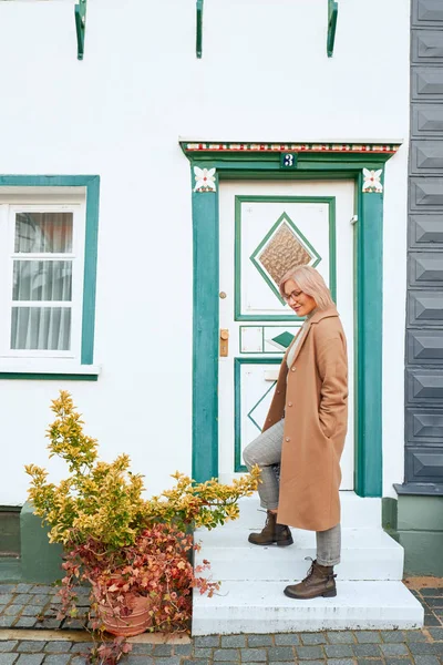 Young beautiful girl in autumn coat. Travels around the European city in the autumn. Cheerful, smiling lady. old houses, paving stones, vintage style, old Europe.