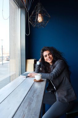 Kafede oturan ve notlar yazma kadın.