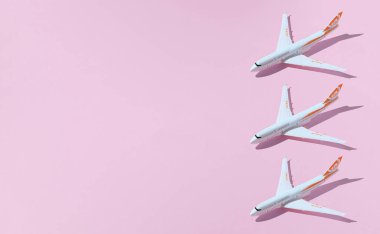 Modeller, pembe arka planda uçaklar. Uçaklarla seyahat kavramı