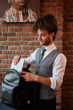 Sırt çantasında dizüstü bilgisayar taşıyan çekici sakallı genç adam.