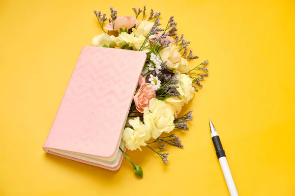 Pink Notepad with Flowers over yellow background. Spring mood