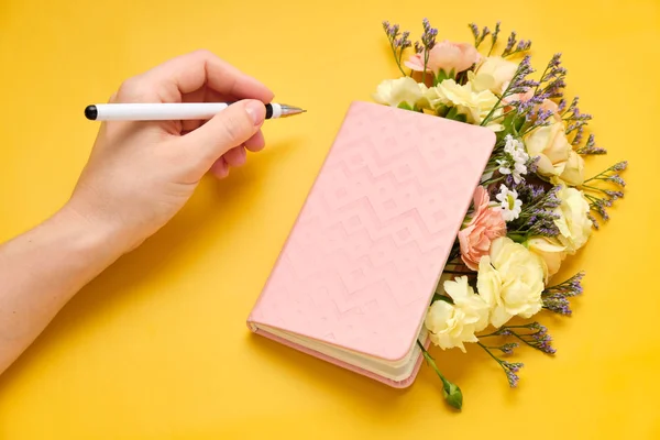 Pink Notepad with Flowers over yellow background. Spring mood