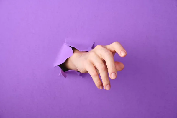 A kéz átszúródik egy lyukon a papír háttéren. — Stock Fotó
