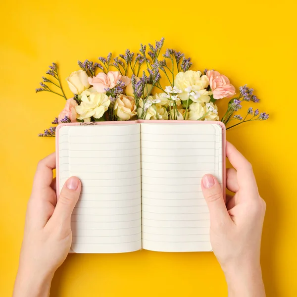 Bloc de notas rosa con flores sobre fondo amarillo. Humor de primavera — Foto de Stock