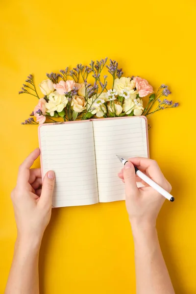 Bloc de notas rosa con flores sobre fondo amarillo. Humor de primavera — Foto de Stock