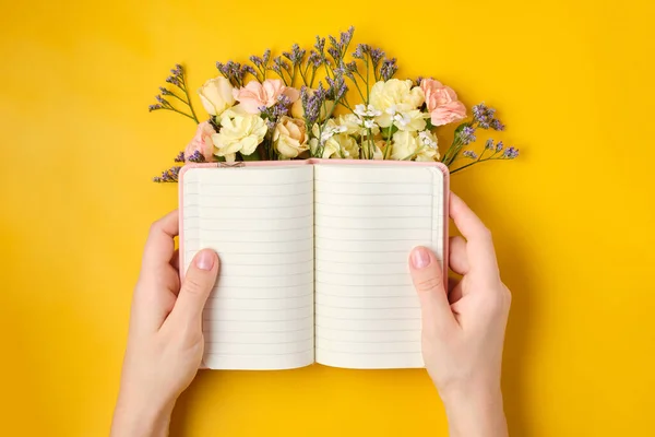 Bloc de notas rosa con flores sobre fondo amarillo. Humor de primavera — Foto de Stock