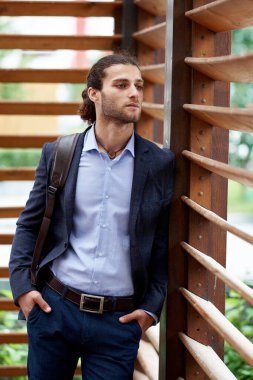 Sırt çantalı, klasik takım elbiseli çekici sakallı genç adam.