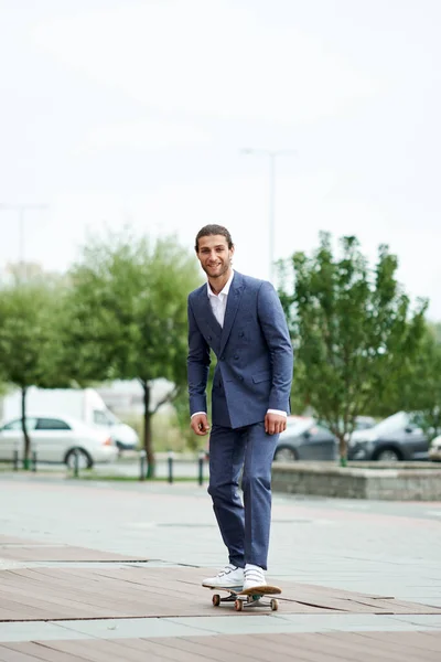 Attraktiver bärtiger junger Mann im klassischen Anzug auf dem Skateboard. Eleg — Stockfoto